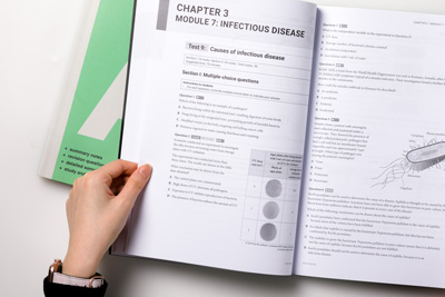 A designer holds a page open to show the chapter opener for Module 7 on infectious disease. 