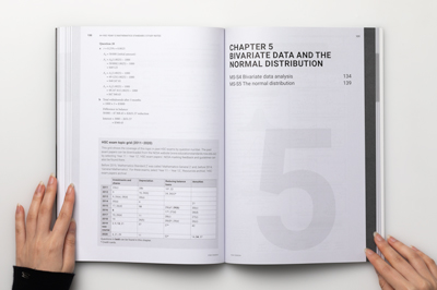 Designer holding open a page spread showing a topic grid and chapter opener.