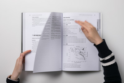 A photo of a designer flicking through pages of Cengage A+ HSC Year 12 Physics Practice Exams.