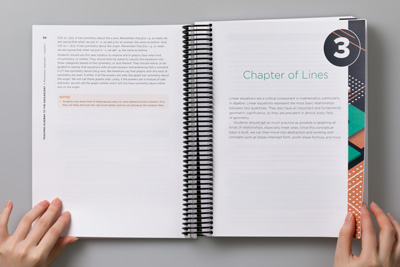 A designer holding the book open to show the design of a chapter opener (Chapter 3, Chapter of Lines).